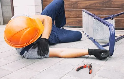 A worker laying on the ground with a tool box.